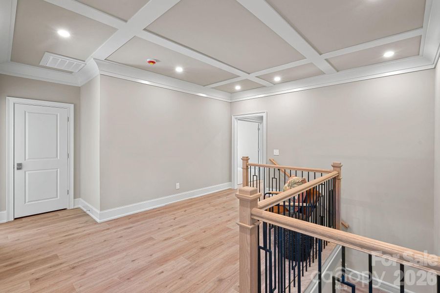 The second-floor landing welcomes you with a gorgeous coffered ceiling, drawing the eye upward and setting the tone for the home’s thoughtfully designed upper level.