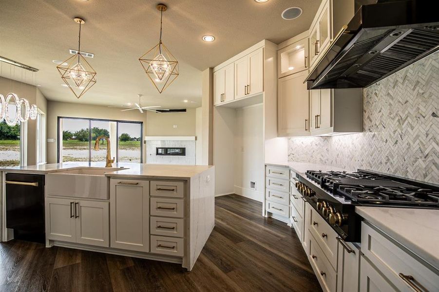 Kitchen with large farmhouse sink, pendant light fixtures, 6 burner gas stove & lots of cabinets.