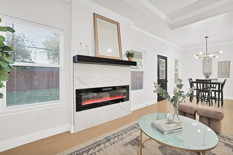 Living room featuring wood-style flooring, crown molding, a healthy amount of sunlight, and a premium fireplace