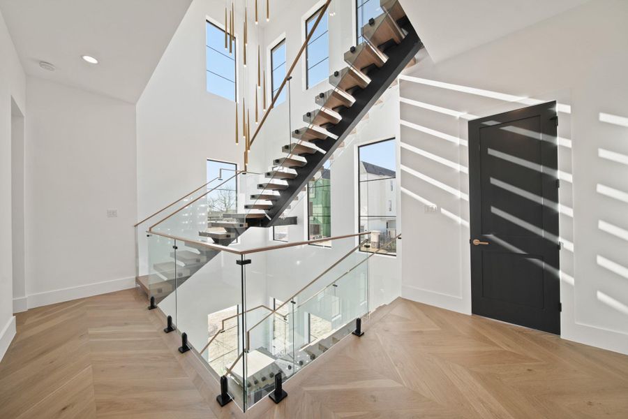 Incredible views of the floating stairs with panel glass railings with the designer chandelier coming down from the third floor.