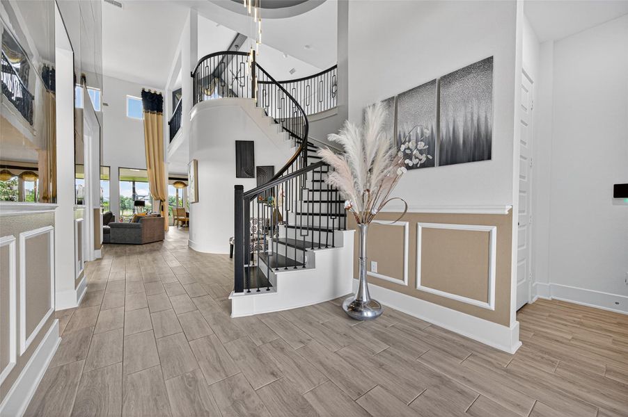 This photo showcases a modern, spacious entryway with a stylish spiral staircase, elegant wood flooring, and high ceilings. The open floor plan extends to a bright living area with large windows, offering a welcoming and airy atmosphere. This photo showcases a modern, spacious entryway with a stylish spiral staircase, elegant wood flooring, and high ceilings. The open floor plan extends to a bright living area with large windows, offering a welcoming and airy atmosphere.