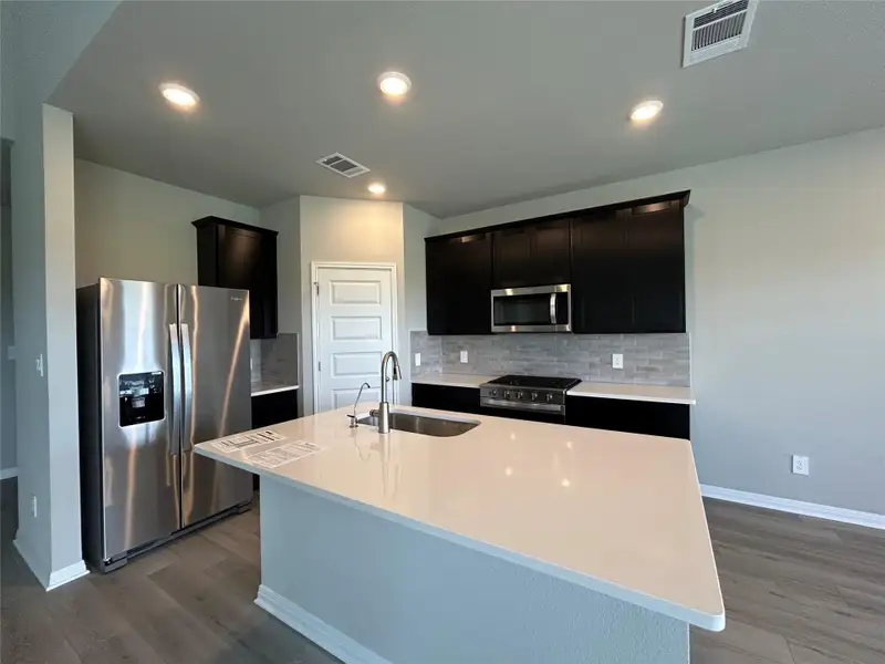 Kitchen featuring stainless steel appliances, light wood-type flooring, decorative backsplash, and recessed lighting
