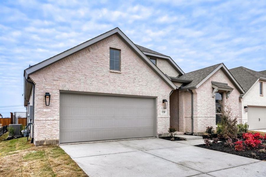 View of front of home featuring concrete driveway, brick siding, and roof with shingles
