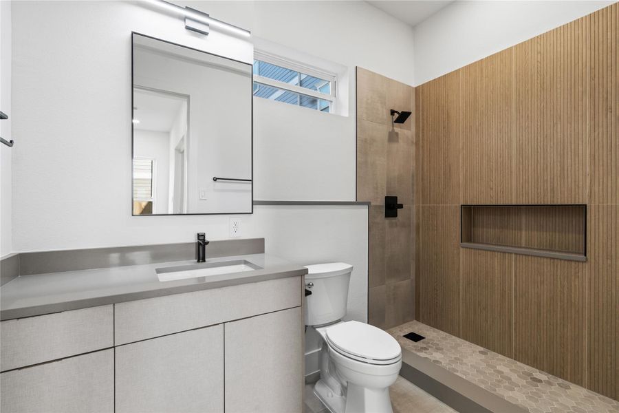 Sleek, sculptural, and quietly luxurious—the first-floor bath is a masterclass in understated design. Vertical wood-look tile adds architectural texture, while matte black fixtures and integrated shelving bring both function and form. A calming, spa-like palette invites daily rituals to feel just a bit more refined. Sleek, sculptural, and quietly luxurious—the first-floor bath is a masterclass in understated design. Vertical wood-look tile adds architectural texture, while matte black fixtures and integrated shelving bring both function and form. A calming, spa-like palette invites daily rituals to feel just a bit more refined.
