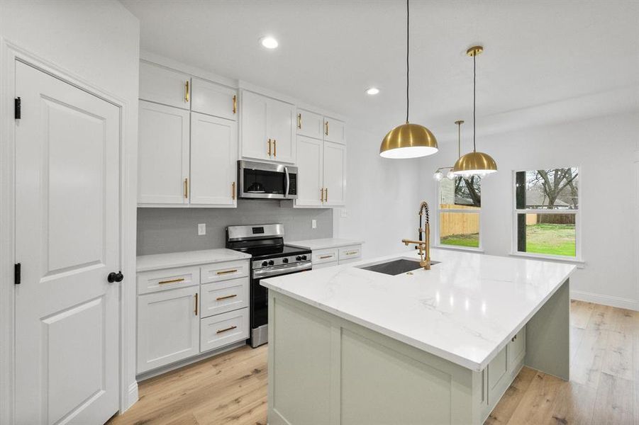 Kitchen featuring backsplash, light wood-style flooring, appliances with stainless steel finishes, white cabinetry, and a sink