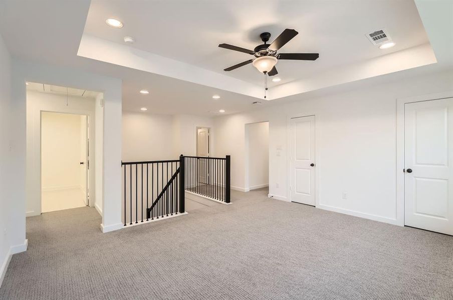 Empty room featuring a tray ceiling and light carpet