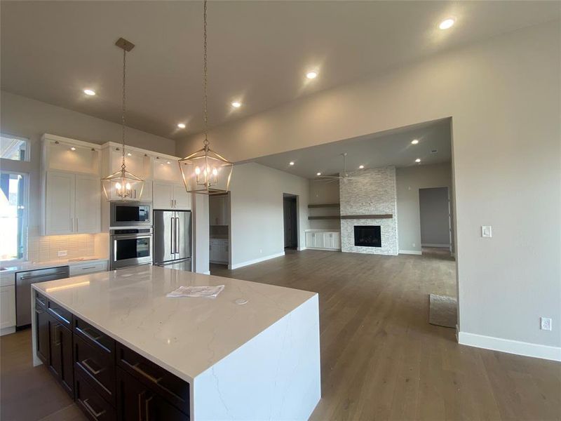 Kitchen featuring white cabinets, appliances with stainless steel finishes, a kitchen island, light stone countertops, and open floor plan