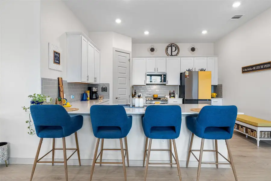 Kitchen with a peninsula, white cabinets, light wood-style floors, tasteful backsplash, and recessed lighting Kitchen with a peninsula, white cabinets, light wood-style floors, tasteful backsplash, and recessed lighting