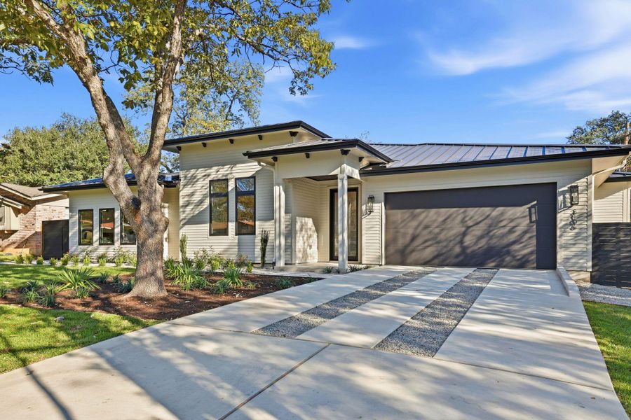 View of front of property with driveway, a metal roof, a standing seam roof, and an attached garage