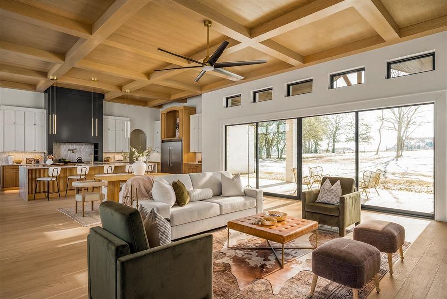 Open-concept living space featuring wood-finish coffered ceilings, expansive sliding glass doors, and light wood-finish flooring