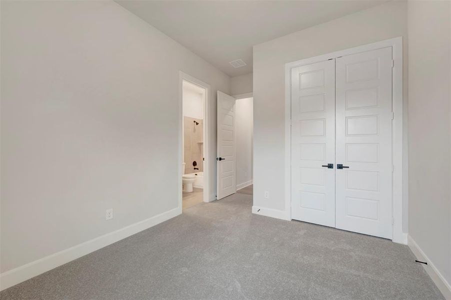 Unfurnished bedroom with light carpet, a closet, and ensuite bath