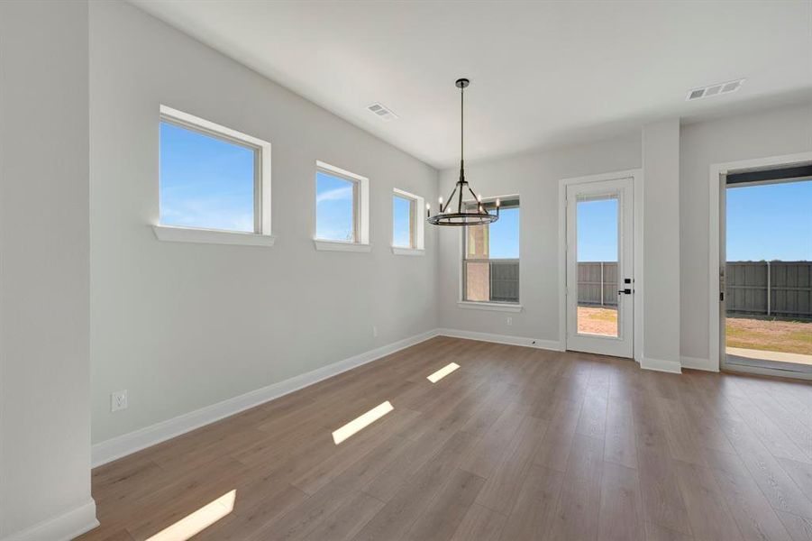 Unfurnished dining area with dark wood-style floors and hanging lights