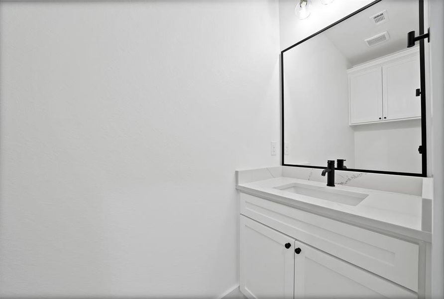 White shaker-style vanity with matte black hardware, integrated rectangular sink, and quartz countertop White shaker-style vanity with matte black hardware, integrated rectangular sink, and quartz countertop
