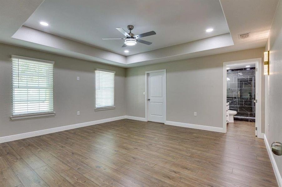 Unfurnished room featuring a raised ceiling, wood-type flooring, ceiling fan, and recessed lighting