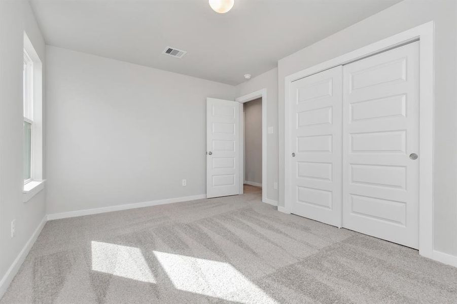 Generously sized secondary bedrooms, complete with spacious closets and soft, inviting carpeting. Enjoy abundant natural light streaming in through the large windows. Sample photo of completed home with similar floor plan. Actual colors and selections may vary.