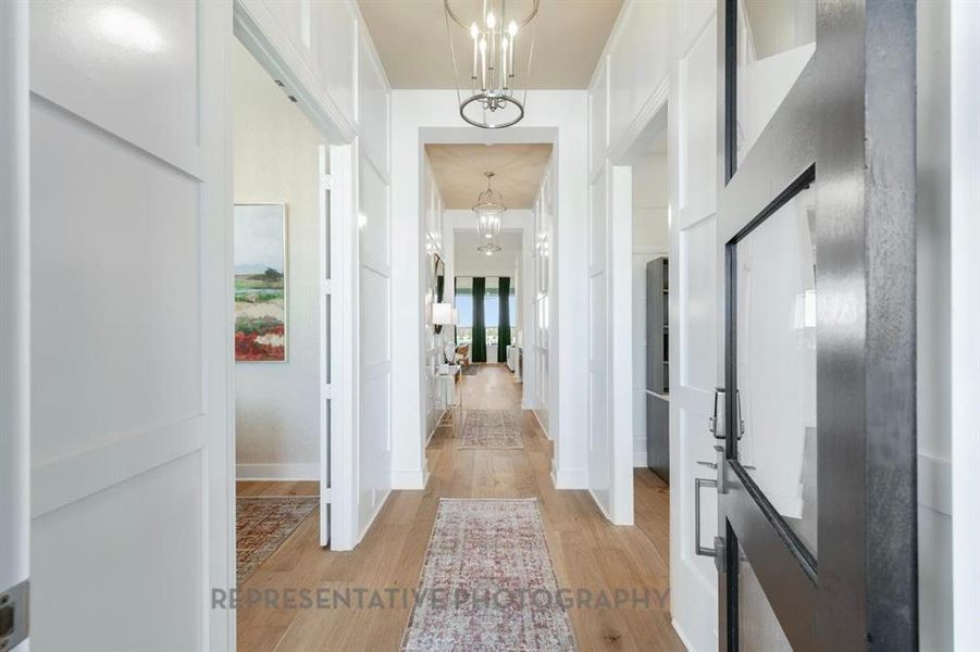Corridor featuring light wood finished floors and a chandelier