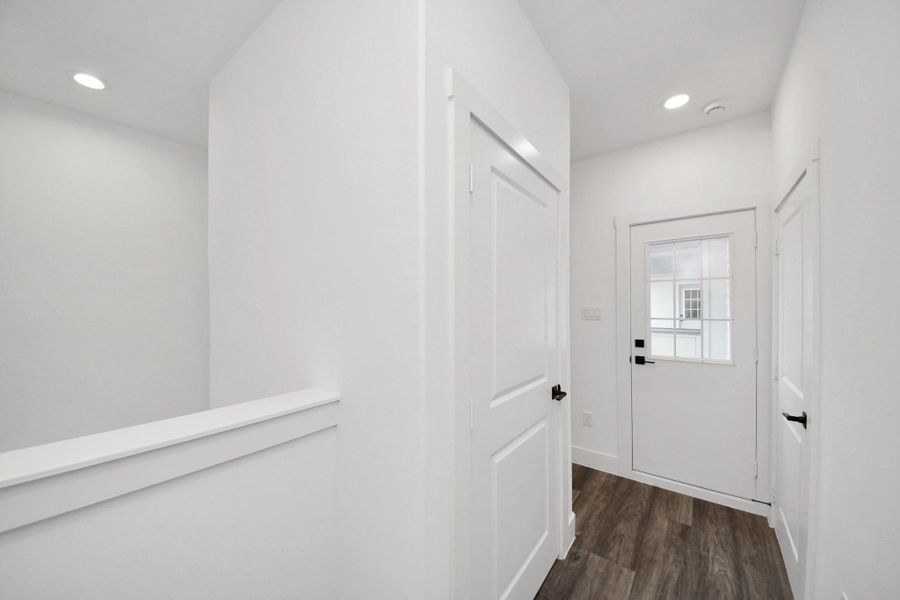 Bright and modern entryway with white walls and doors, featuring wood-look flooring and recessed lighting. Bright and modern entryway with white walls and doors, featuring wood-look flooring and recessed lighting.