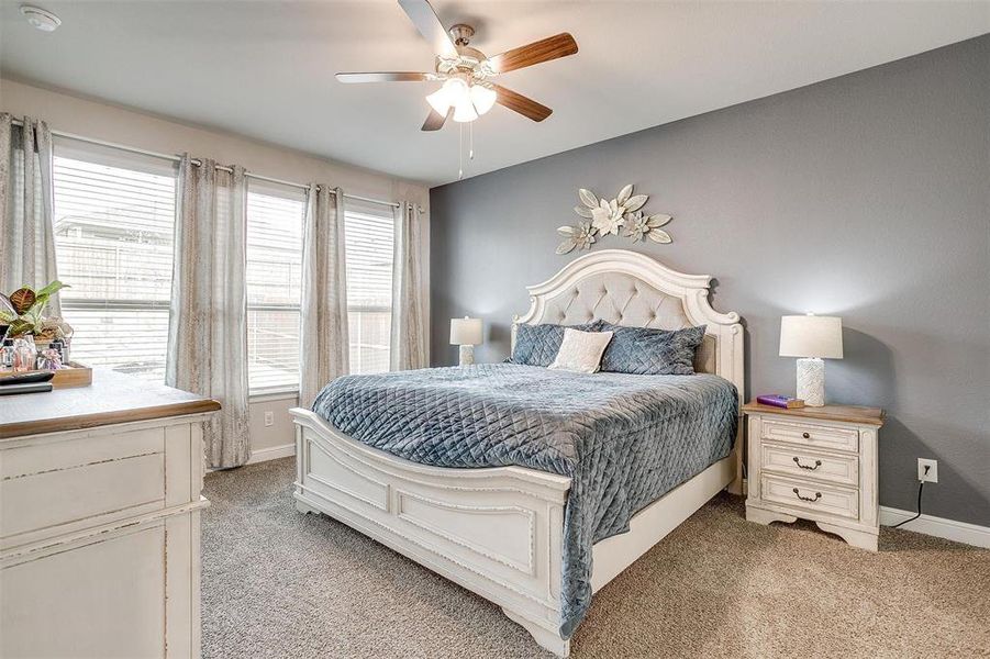 Bedroom with light colored carpet, baseboards, and multiple windows