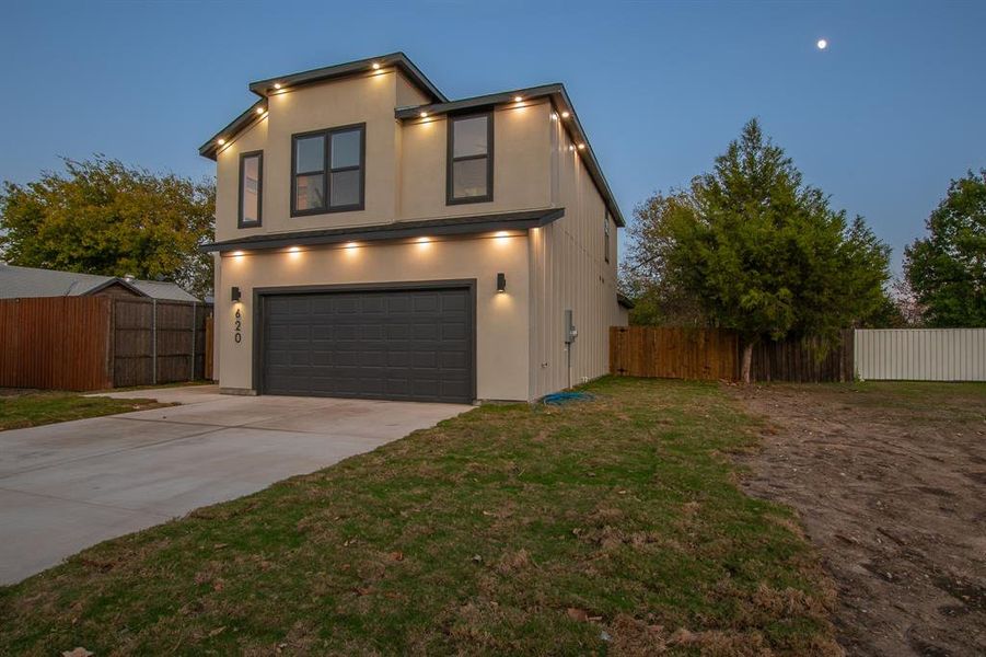 View of front of property featuring a garage and a yard