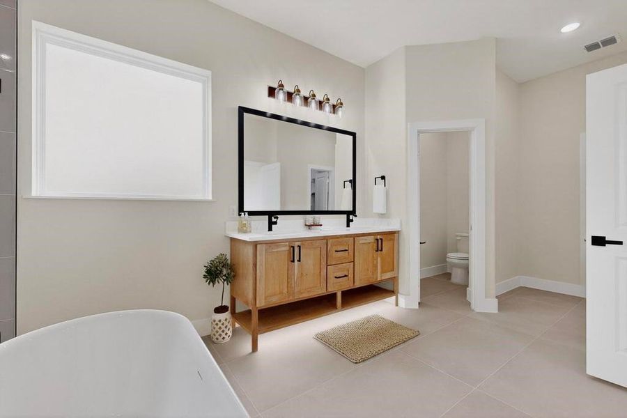 Full bathroom featuring light tile patterned floors, a freestanding tub, double vanity, and recessed lighting Full bathroom featuring light tile patterned floors, a freestanding tub, double vanity, and recessed lighting