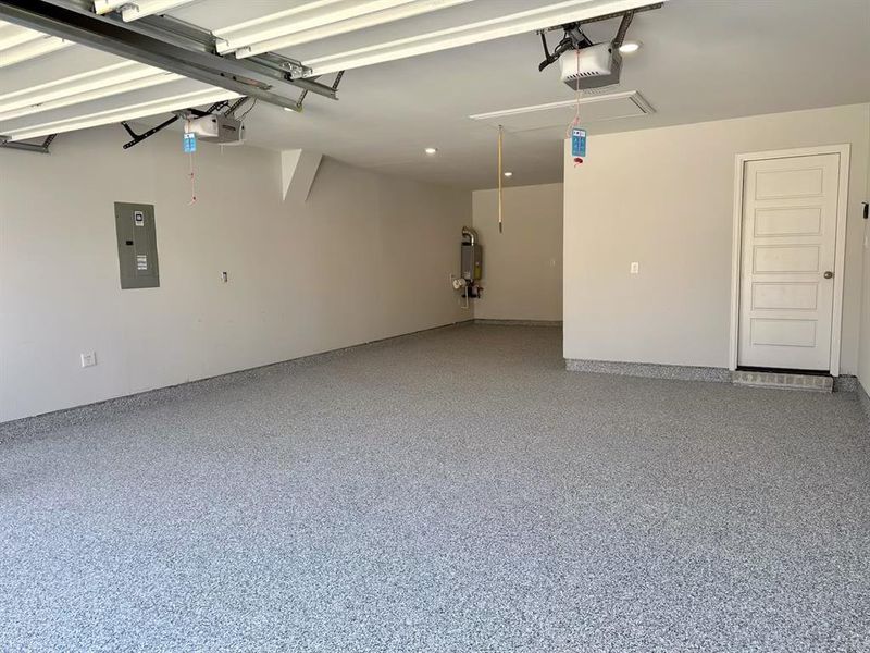 Garage featuring water heater, a garage door opener, and electric panel Garage featuring water heater, a garage door opener, and electric panel