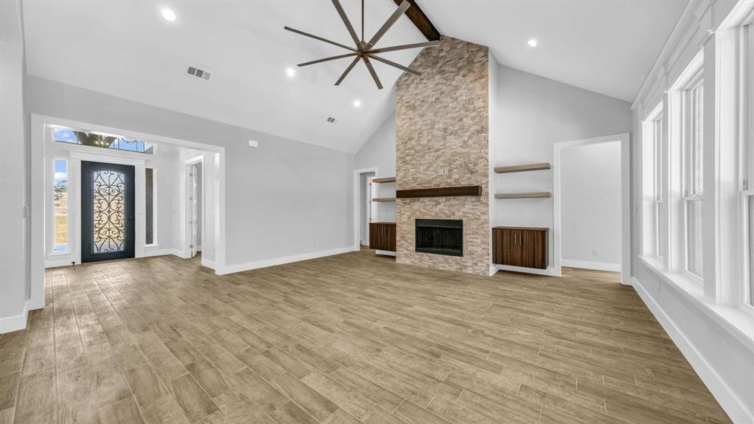 Kitchen with light wood-type flooring, ceiling fan, hanging light fixtures, a center island with sink, and backsplash