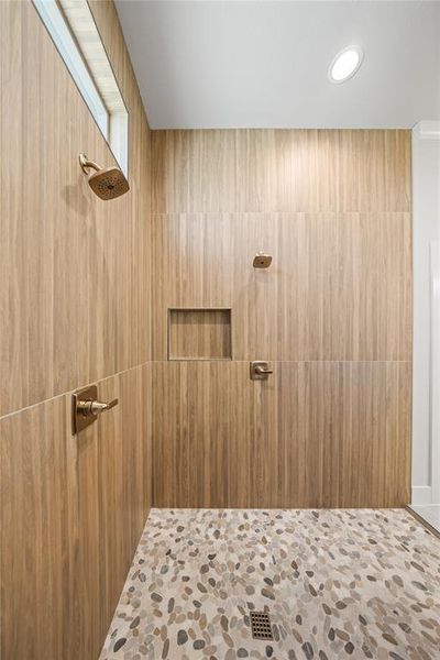 Bathroom with a tile shower, stone finish flooring, and recessed lighting