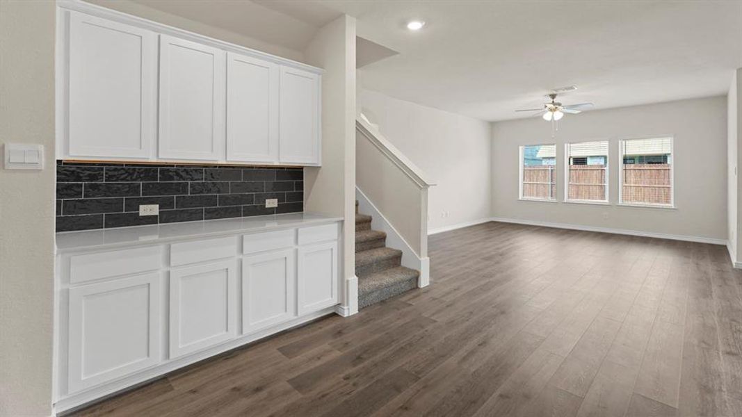 Unfurnished living room with stairs, dark wood-type flooring, a ceiling fan, and recessed lighting Unfurnished living room with stairs, dark wood-type flooring, a ceiling fan, and recessed lighting