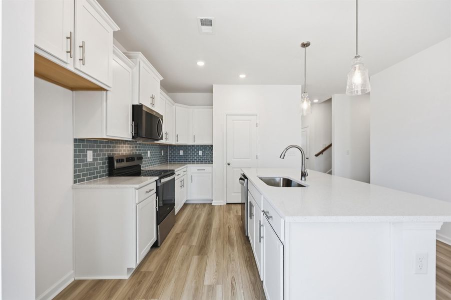 Kitchen featuring stainless steel appliances, light stone countertops, hanging light fixtures, a kitchen island with sink, and recessed lighting Kitchen featuring stainless steel appliances, light stone countertops, hanging light fixtures, a kitchen island with sink, and recessed lighting