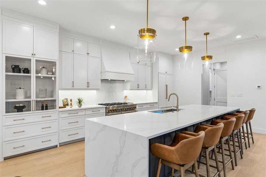 Stunning chef’s kitchen with expansive waterfall island, custom cabinetry, and premium appliances, designed for both everyday living and entertaining.