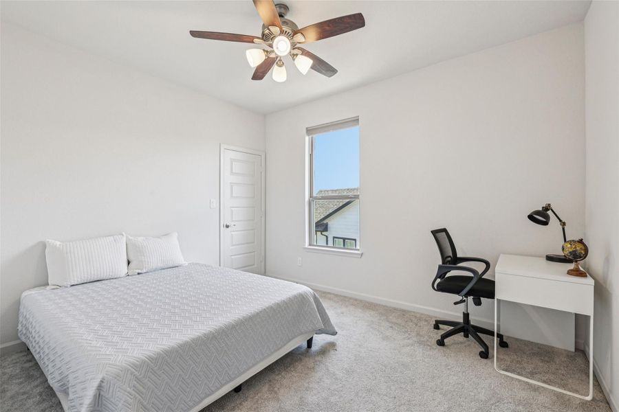 The room features light-colored walls and carpeting, a window, and a ceiling fan with integrated lighting