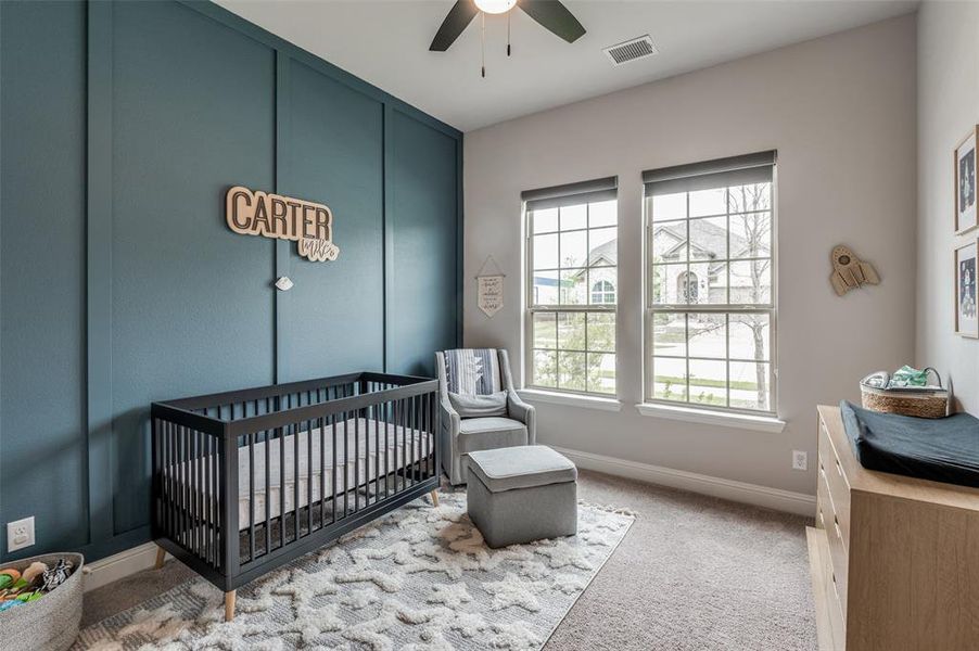 Bedroom with a crib, carpet floors, and ceiling fan