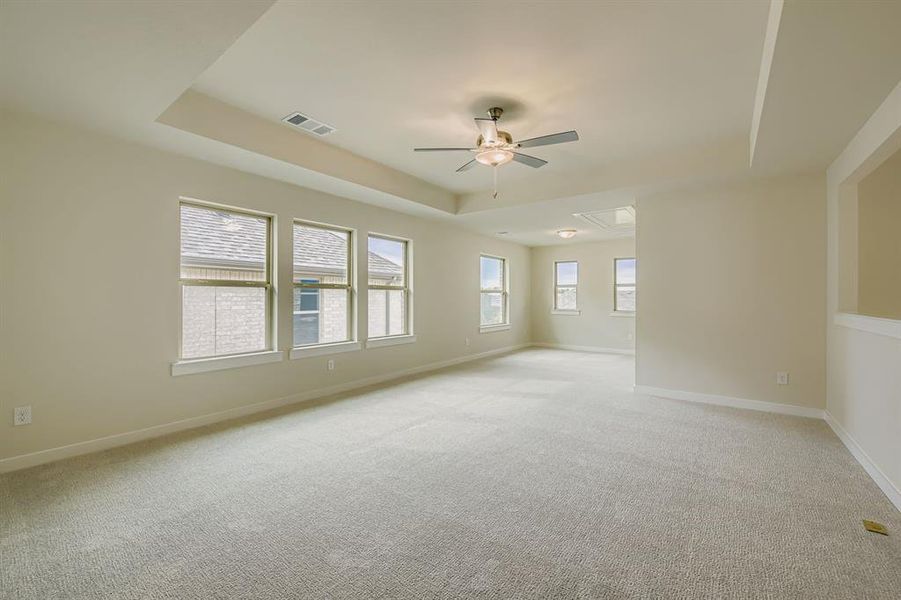 Game room featuring a tray ceiling, light carpet, and a ceiling fan Game room featuring a tray ceiling, light carpet, and a ceiling fan