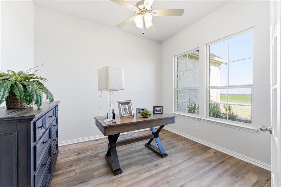 Office with light wood-style floors and ceiling fan