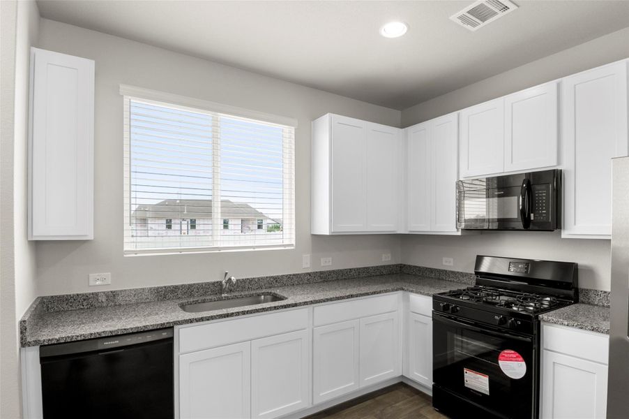 Kitchen featuring black appliances, plenty of natural light, white cabinetry, dark wood-style floors, and recessed lighting Kitchen featuring black appliances, plenty of natural light, white cabinetry, dark wood-style floors, and recessed lighting