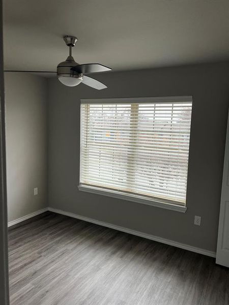 Spare room featuring a healthy amount of sunlight, ceiling fan, and hardwood / wood-style floors