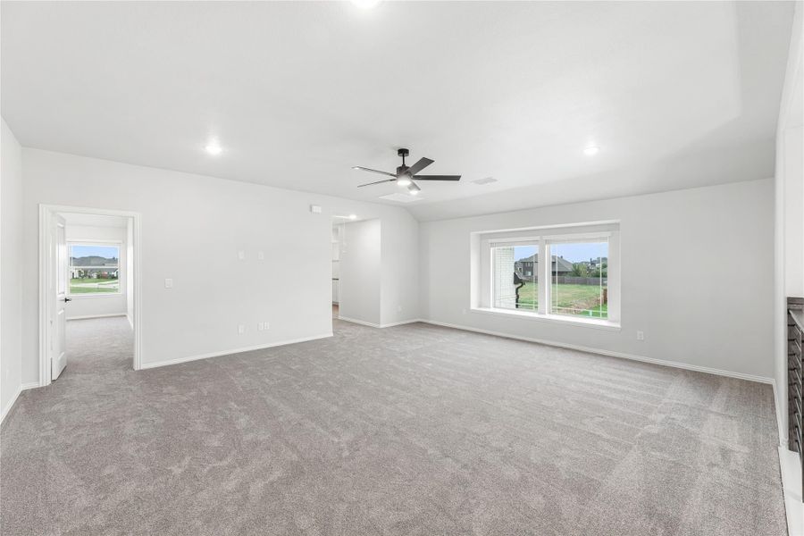 Spacious living room with gray carpet, ceiling fan, and large window overlooking backyard