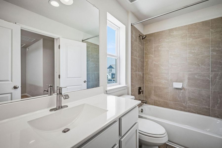A classic tub and shower combination sits adjacent to a modern vanity with integrated sink. A classic tub and shower combination sits adjacent to a modern vanity with integrated sink.