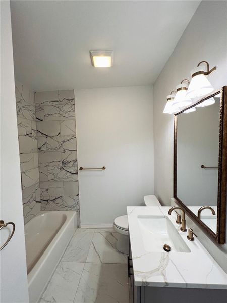 Bathroom featuring marble finish floor, vanity, and toilet Bathroom featuring marble finish floor, vanity, and toilet