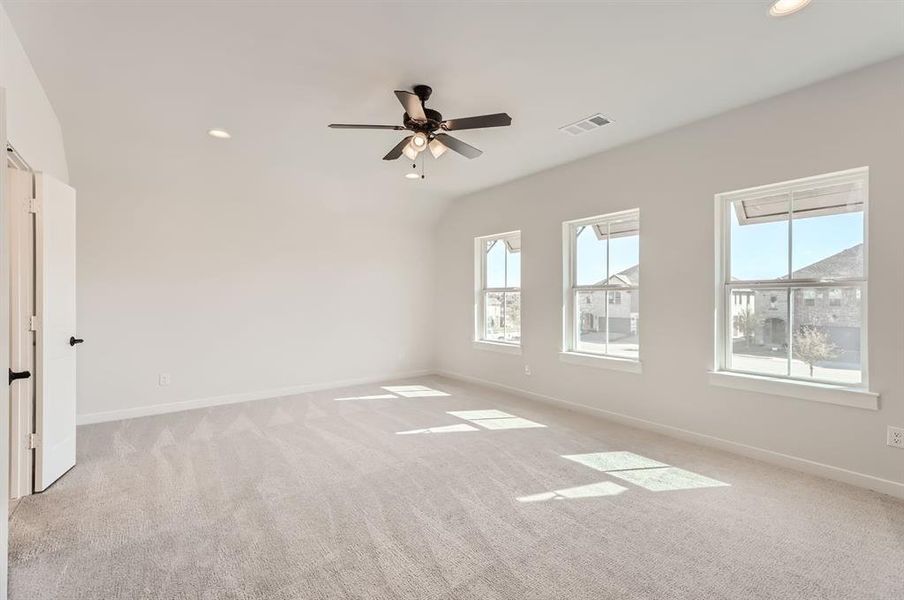 Carpeted spare room with ceiling fan and a healthy amount of sunlight