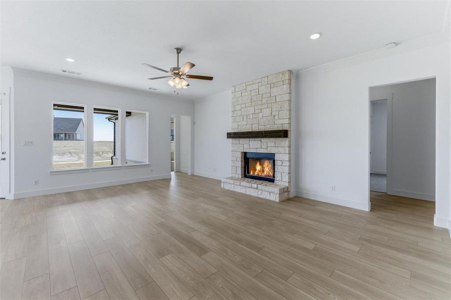 Unfurnished living room featuring a ceiling fan, a fireplace, light wood-style floors, ornamental molding, and recessed lighting