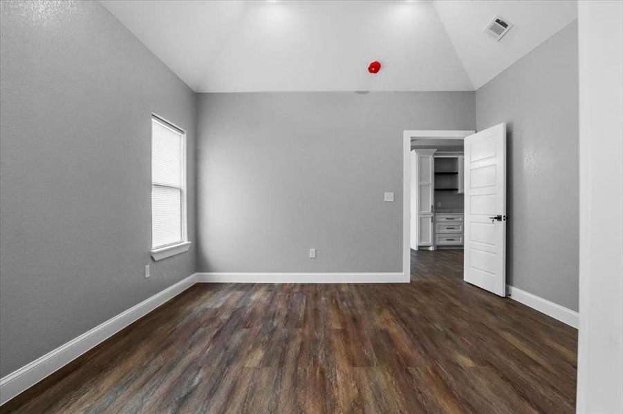 Unfurnished bedroom featuring dark hardwood / wood-style floors and lofted ceiling