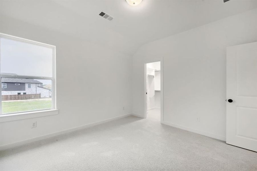 Spacious room featuring light-colored carpeting, a large window, and a walk-in closet with built-in shelving