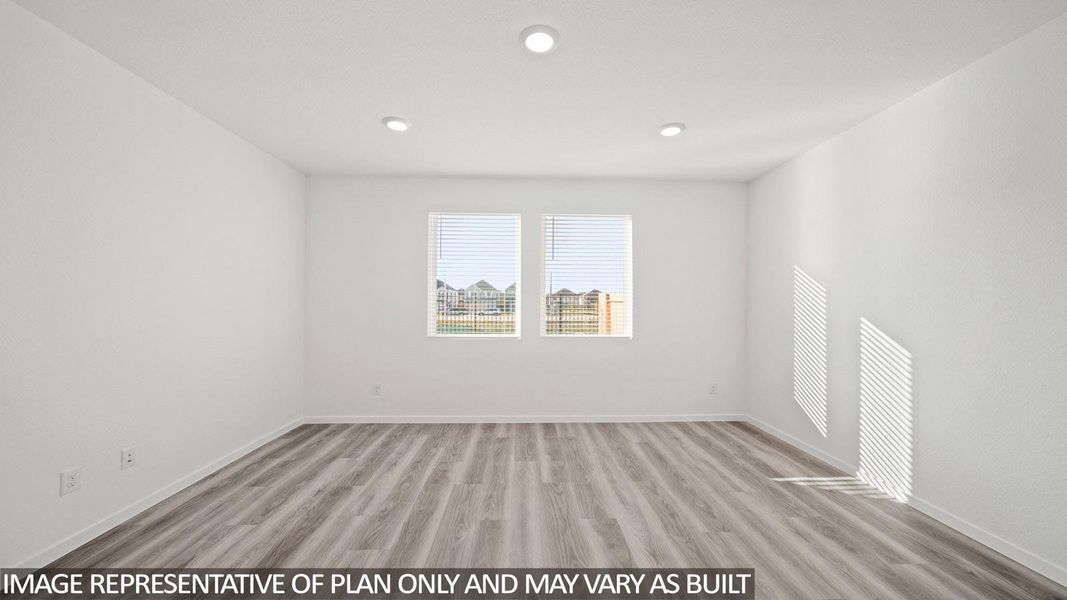 Spacious room with wood-finish flooring, two windows, recessed lighting, and white baseboards