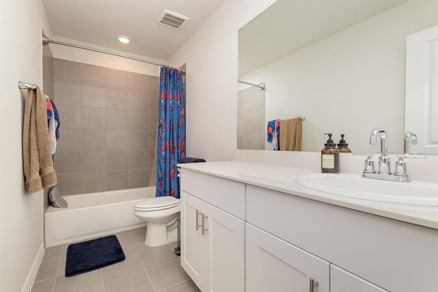 Full bathroom featuring shower / bathtub combination with curtain, tile patterned flooring, vanity, and toilet