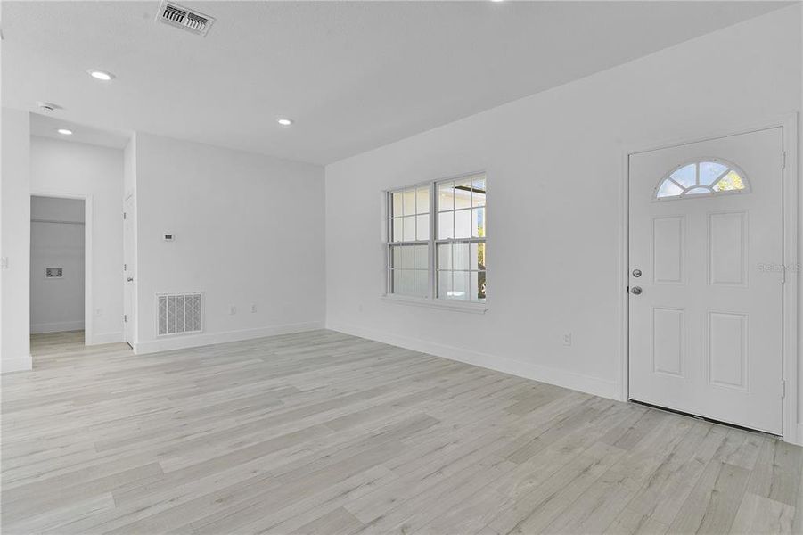 Living room across the front of the home, with front entry door on the right and laundry room to the left side of the picture