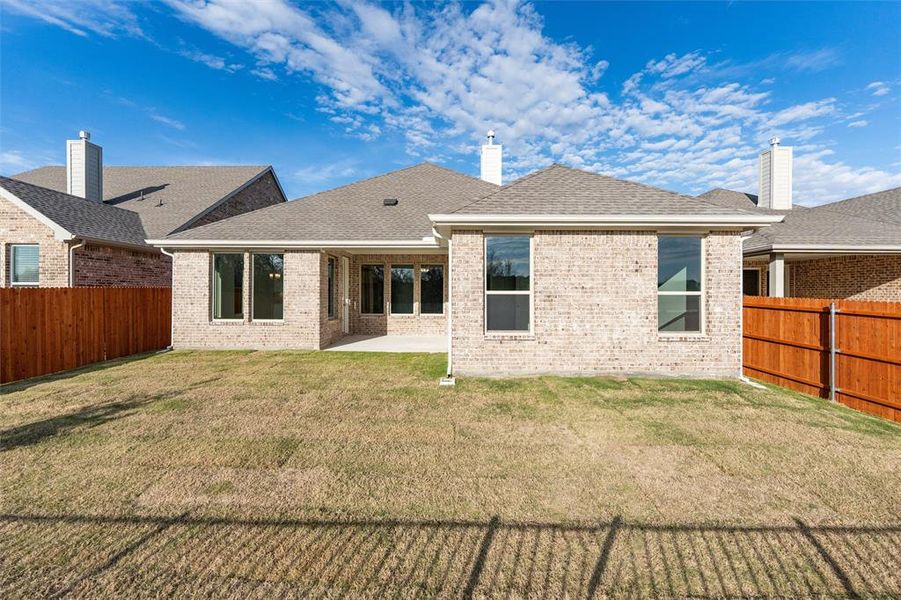 Rear view of property with a shingled roof, a fenced backyard, a patio area, and brick siding