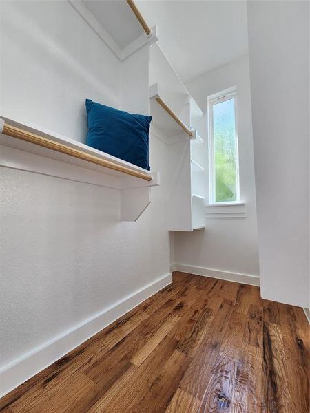 Walk in closet with hardwood / wood-style flooring