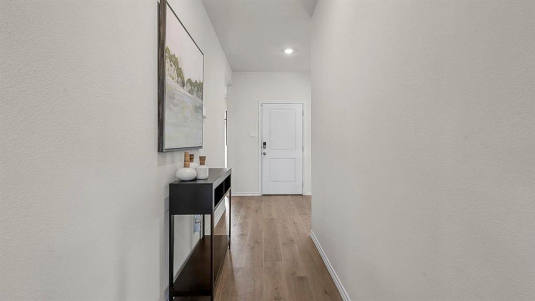 The entryway features light-toned flooring, a light-colored wall, and a white door, creating a bright and inviting atmosphere