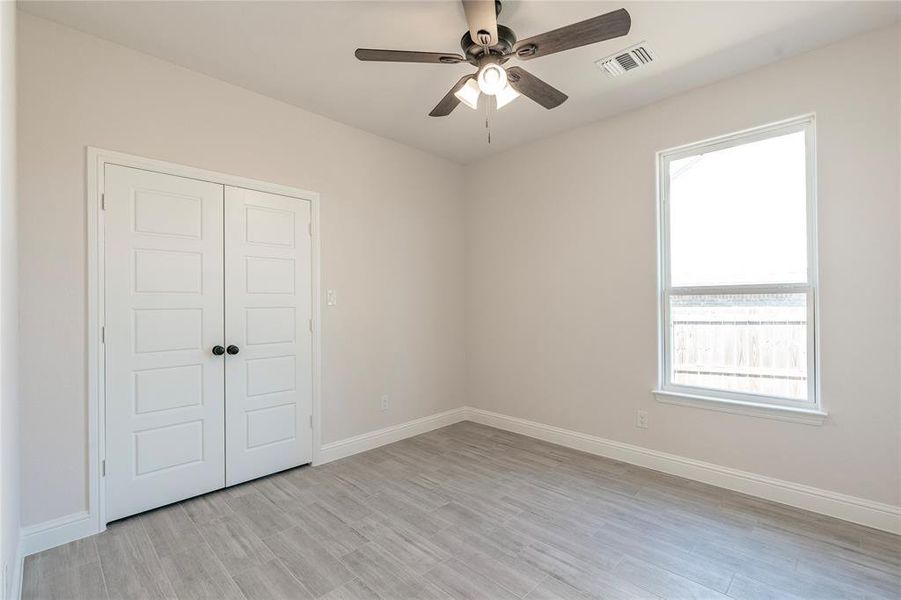 Unfurnished bedroom featuring ceiling fan, a closet, light hardwood / wood-style flooring, and multiple windows